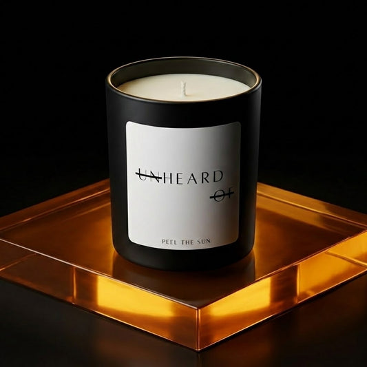 UNHEARD OF Peel the Sun luxury candle, matte black jar with minimalist label, 8oz hand-poured coconut wax, smoked grapefruit and kalamansi lime scent.